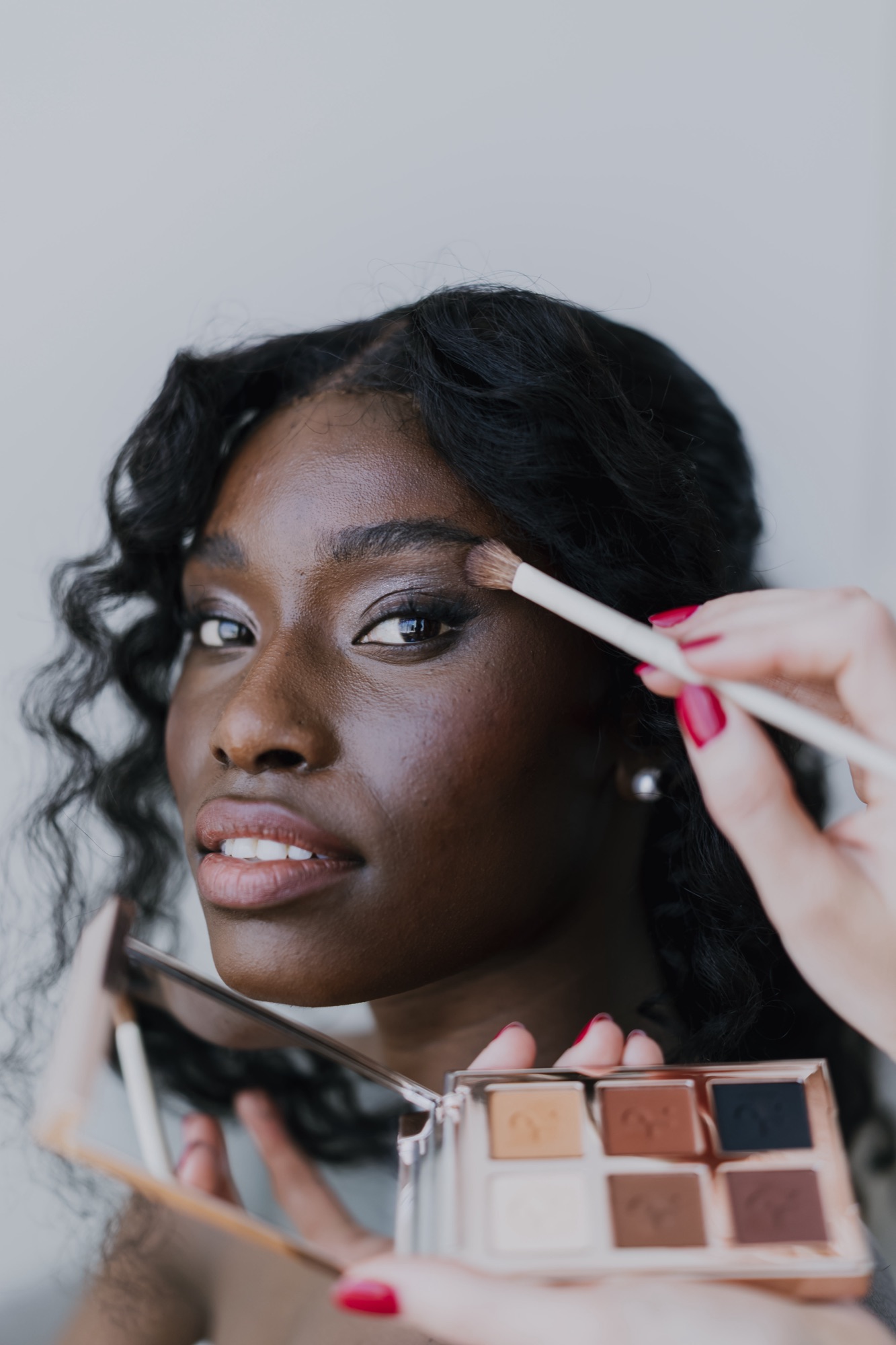 Eyeshadow being applied with a brush and palette during a Glow Charm makeup session
