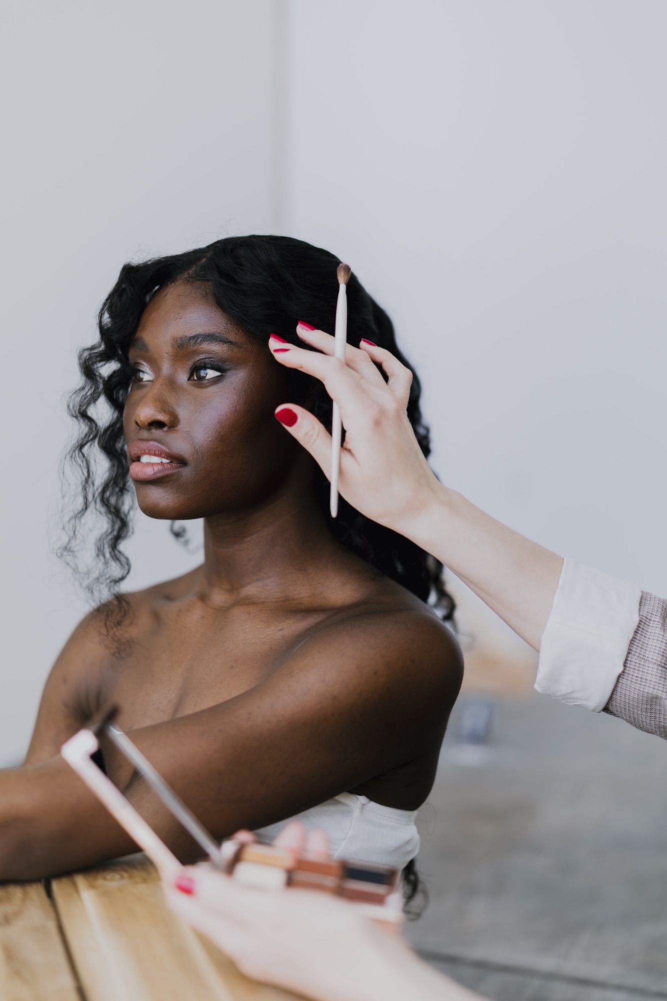 Makeup artist applying eyeshadow with a brush, an eyeshadow palette held in the foreground